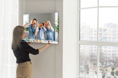 Galeri ambalajlı tuval baskısı. Kadın fotoğrafçılığı beyaz duvara asıyor. Ellerinde resim bezi izi var..