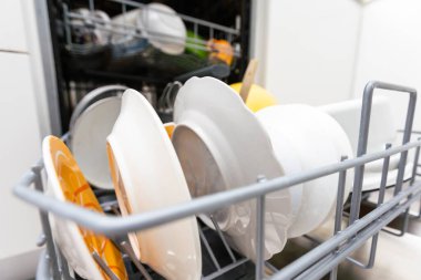 Bulaşık makinesini beyaz mutfakta temiz bulaşıklarla açın..