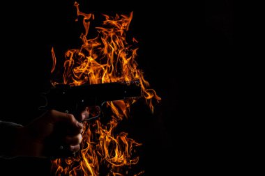 The hand presses the trigger of the gun and the flame from the shot.