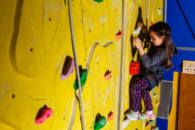 Küçük kız kaya duvarına tırmanıyor..