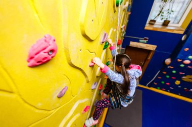 Küçük kız kaya duvarına tırmanıyor..