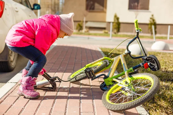 a little girl pumps up a bicycle tire