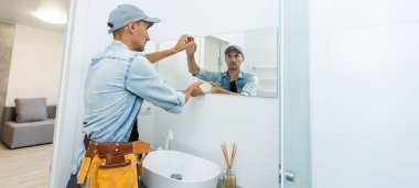 Ustabaşı banyoya ayna yerleştiriyor.