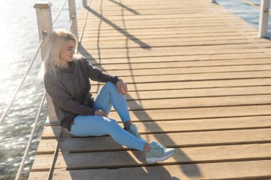 Genç bir kadın güneşli bir günde denizin önünde dubada.