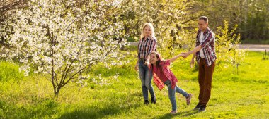 Mutlu bir aile baharda çiçek açan bir bahçede birlikte iyi vakit geçirir..