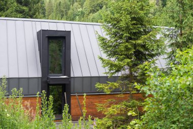 Modern tasarlanmış dış görünüşü büyük yeşil bahçe ve ağaçları olan ev..