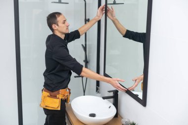 İşçi aynayı banyoya yerleştirir.