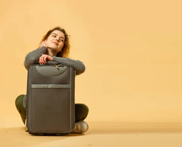 concept of travel. happy woman girl with suitcase and passport on yellow colored background