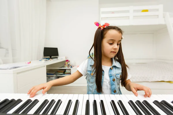 Home lesson on music for the girl on the piano. The idea of activities for the child at home during quarantine. Music concept.