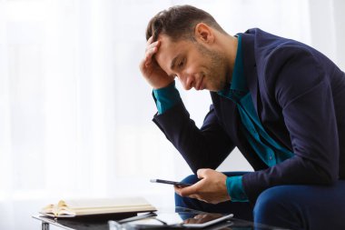 Evde dizüstü bilgisayar ve kağıtlarla çalışan genç bir iş adamı.