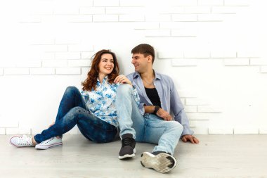 Mutlu adam ve kadın beyaz duvarın arkasında oturuyor.