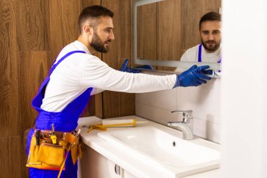 İşçi aynayı banyoya yerleştirir.