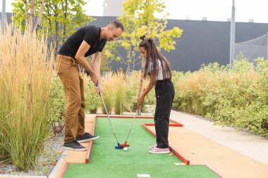 father and daughter playing mini golf.