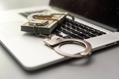 Handcuffs keyboard and dollars above.