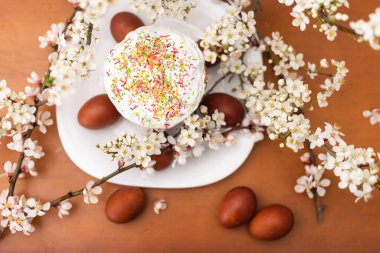 Paskalya pastası, boyanmış yumurta ve çiçek açan dal, ahşap masada bahar kompozisyonu..