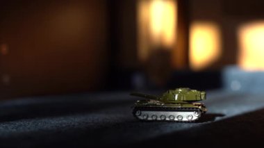 İzole edilmiş uzaktan kumandalı bir oyuncak tankın yakın plan çekimi tareti döndürür ve namludan ateş eder. Askeri çocuklar için oyuncaklar. Ağır silahlarla bir savaş oyunu. RC oyuncak tankı
