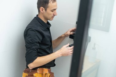 Tesisatçı banyoya duş kabini kuruyor..