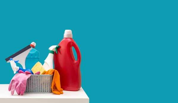 Colorful cleaning set for different surfaces in kitchen, bathroom and other rooms. Empty place for text or logo on blue background. Cleaning service concept.