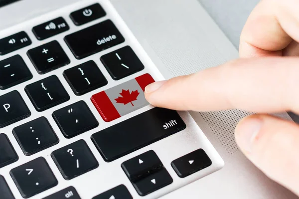 Computer key with the Canada on it. Male hand pressing computer key with Canada flag