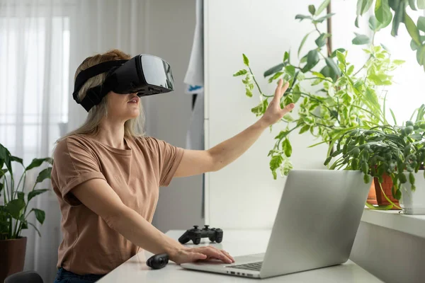 Future is right now. Confident young woman adjusting her virtual reality headset and smiling while sitting at her working place in office.