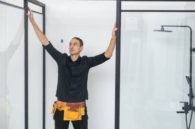 Tesisatçı banyoya duş kabini kuruyor..