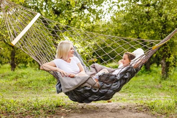 loving family spends time together in summer time enjoy the little things. slow life. mom and little daughter relax in a hammock in the summer in the garden.