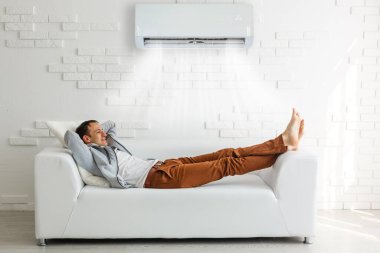 Genç adam evde televizyon yakınındaki kanepede rahatlatıcı