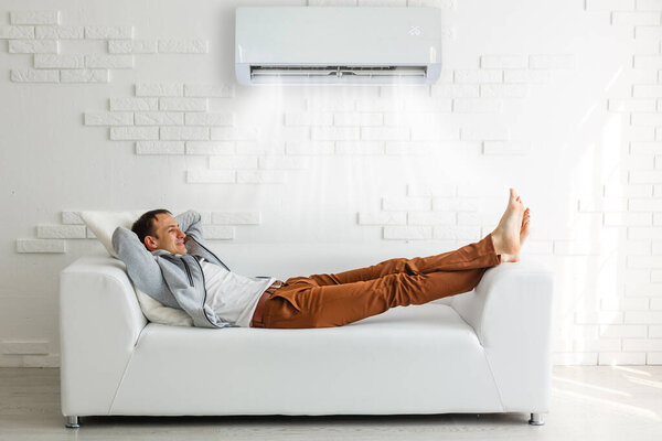 Young Man Relaxing On Sofa Near Television At Home