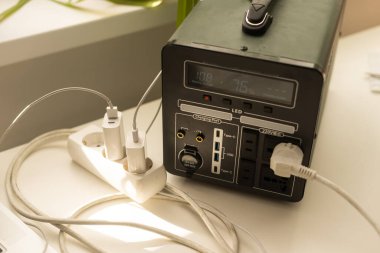 Portable power station charging gadgets near wall.