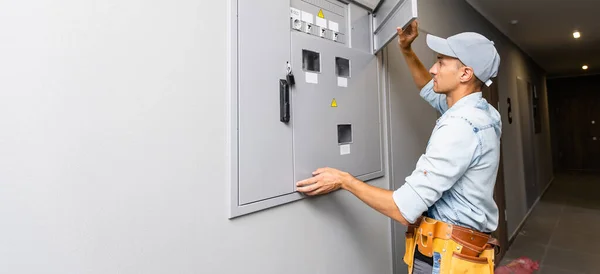 An electrician working on an industrial breaker panel. Model is an actual electrician performing all work to industry codes and safety standards