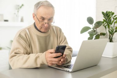 Senior man with eyeglasses connected with laptop at home