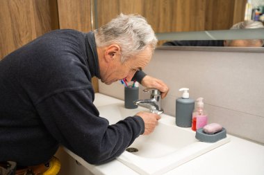Man repairing bathroom faucet with adjustable wrench.