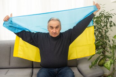 Senior man with Ukrainian flag. Ukraine national flag colors. Pray for Ukraine, stop the war, save Ukraine people and children. No invasion, occupation and terrorism