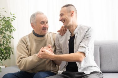 Help needed. Pleasant senior man sitting on the sofa.