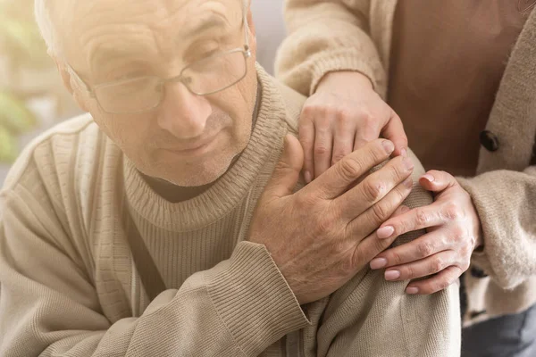 Hands of an elderly man holding the hand of a younger woman.