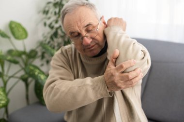 an elderly man hurts his elbow.