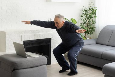 Mature aged man watching video training tutorial online, vlogging and blogging at home on lockdown.