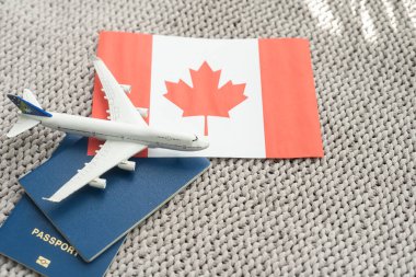 Top view of passport, toy plane, flag of Canada.