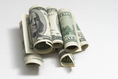 roles dollar notes in front of white background.
