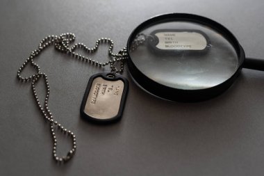 Amerikan askeri künyesi. Rozetinde bir asker ismi var. Büyüteç.