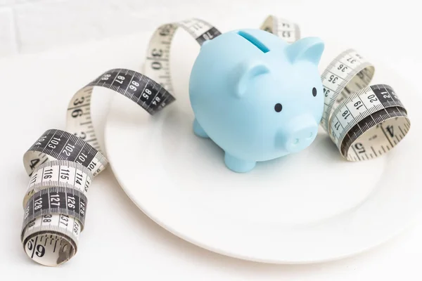 a measuring tape and a piggy bank in a white plate.