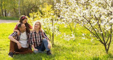 Mutlu bir aile baharda çiçek açan bir bahçede birlikte iyi vakit geçirir..