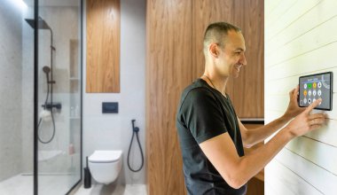 Genç Yakışıklı Adam Akıllı Ev Uygulamasına Ses Komut Veriyor Işıkları Açmak ve Rahatlatıcı Sıcaklığı Ayarlamak için Monitörde.