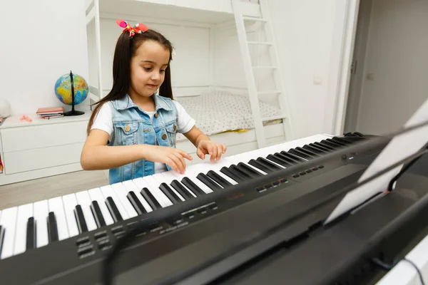 귀여운 소녀가 신시사이저를 연주하는 배우고 있습니다 — 스톡 사진