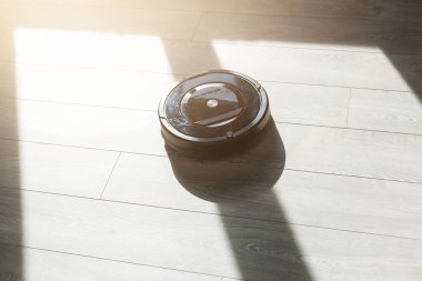 Robot elektrikli süpürge yatak odasında lamine ahşap zemin üzerinde.