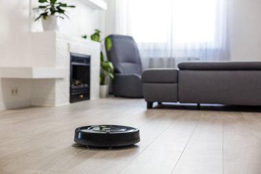 Oturma odasındaki lamine ahşap zeminde robotik süpürge.