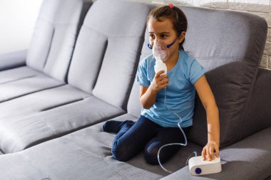 Küçük kız evde nebulizörle solunum yapıyor. çocuk astım spreyi soluma nebulizer buhar tutması öksürük konsepti yatay