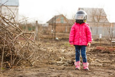 Motokros moto kaskı takmış, koruyucu bir kaskla gülümseyen küçük bir kızın portresi. Motokros kasklı motorcu kız..