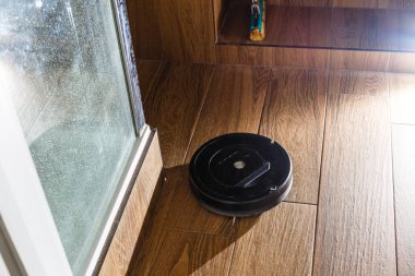 The robot vacuum cleaner drives on the laminate floor. Smart House. Home assistant concept