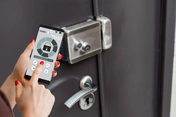 smart house, home automation, device with app icons. Man uses his smartphone with smarthome security app to unlock the door of his house